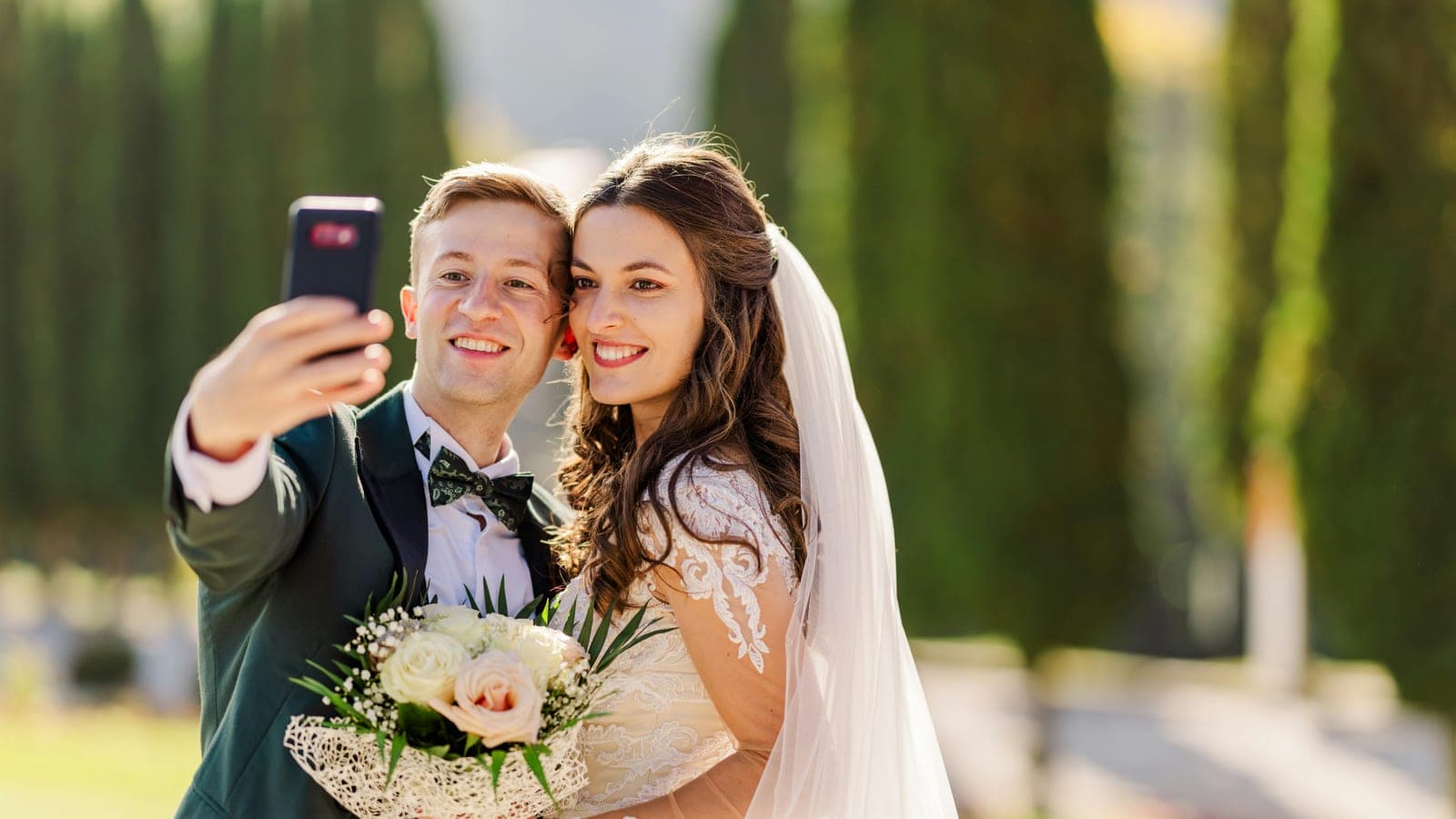 A newly married couple taking a selfie together outdoors